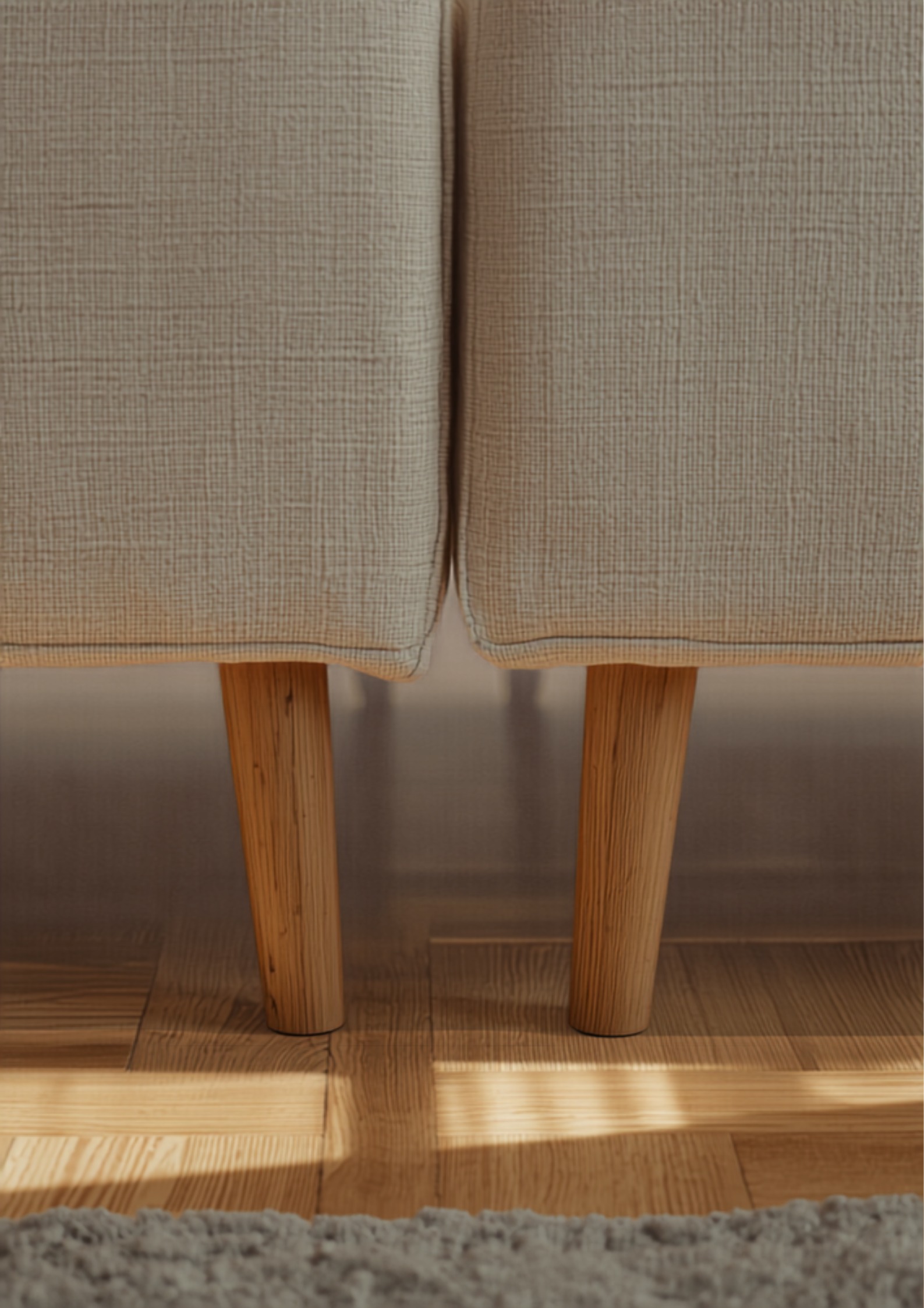 Detail van twee linnen banken die in een L-vorm samenkomen met slanke eiken pootjes op een lichte houten vloer