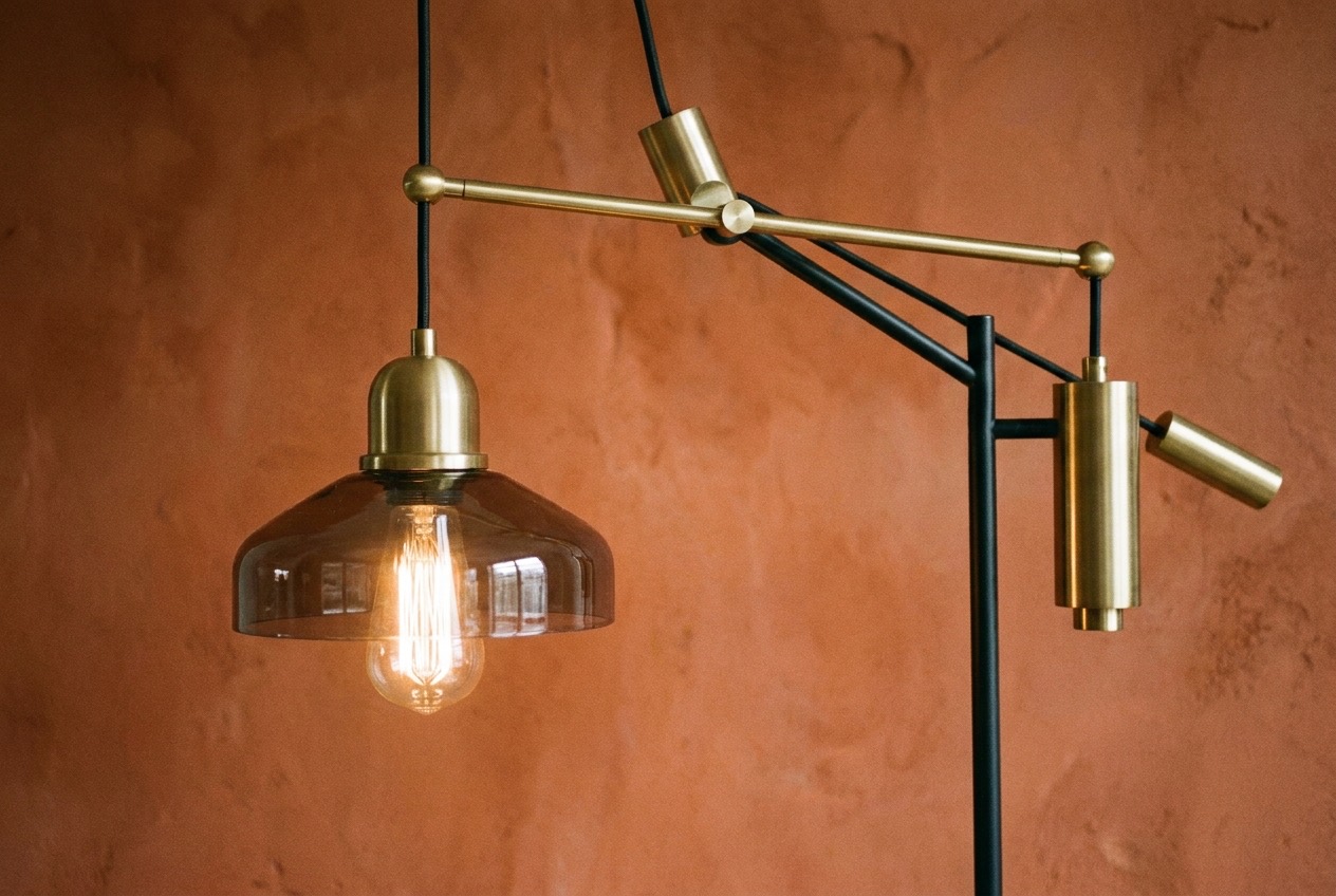 Close-up van een verstelbare modulaire hanglamp met warme gloed tegen een kleikleurige muur